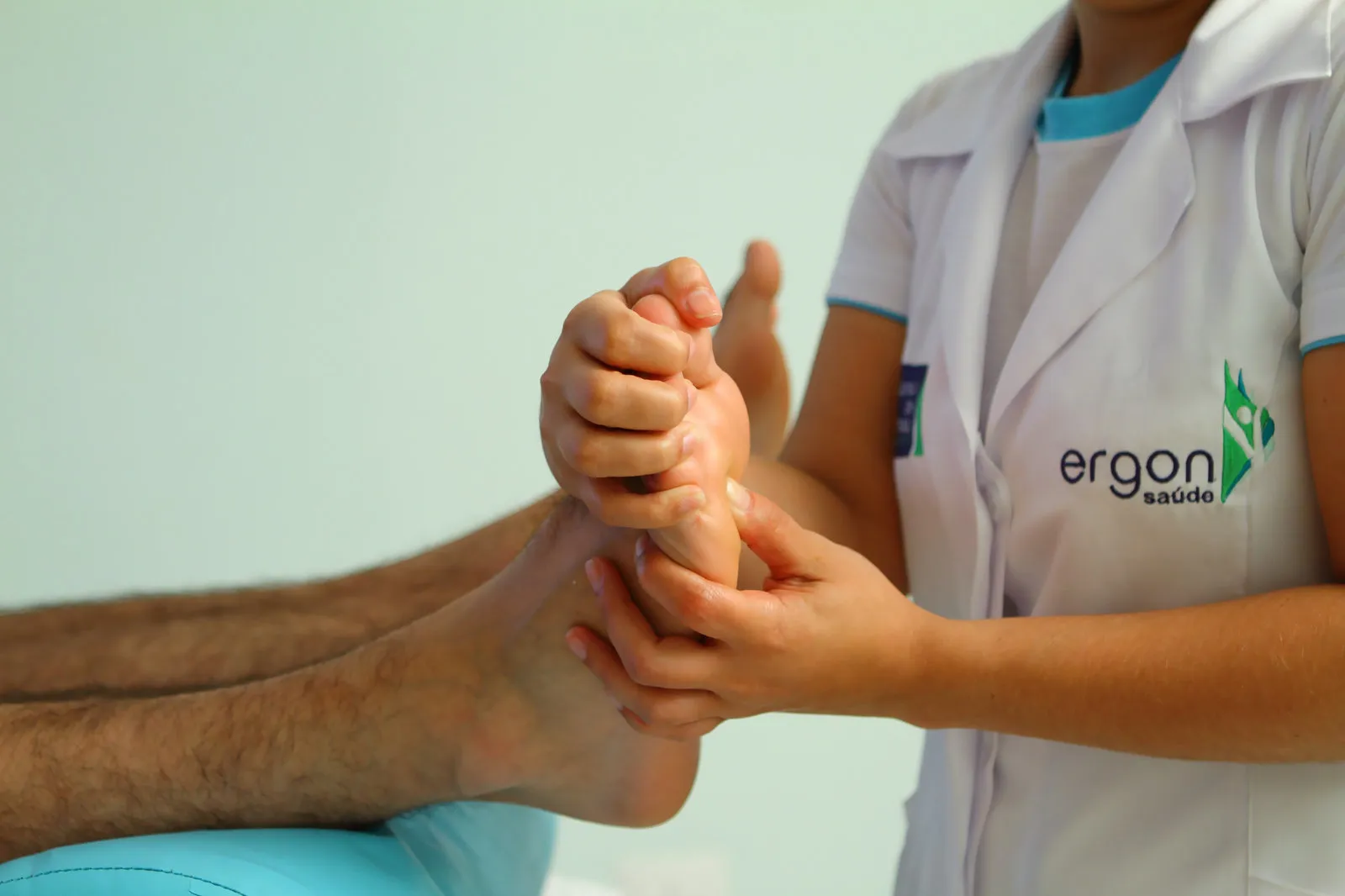 Massoterapeuta da Ergon fazendo reflexologia nos pés de uma cliente